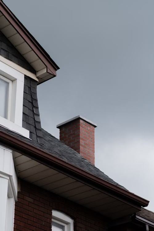 Brick chimney on a shingled roof ready for a chimney inspection
